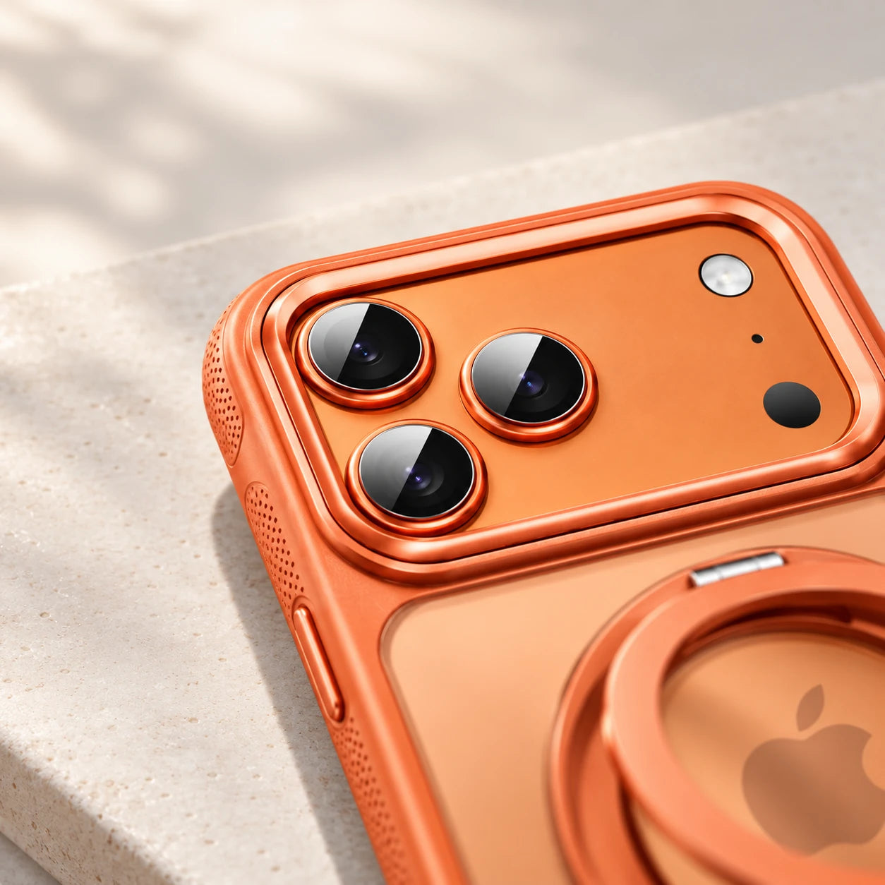 Raised orange camera border surrounding three rear lenses on a phone case with a folding ring stand.